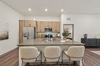 A modern kitchen with a large island and chairs.